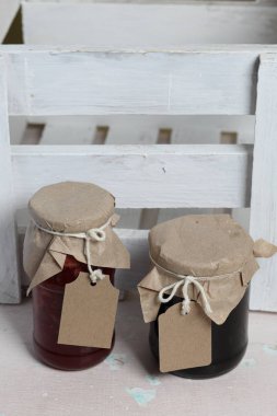 Reçel kavanozları, kağıt ile kaplıdır ve ikiyle bağlanmış. Dize asmak Craft etiketleri. Ahşap tahtaları arka planda.