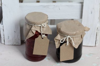 Reçel kavanozları, kağıt ile kaplıdır ve ikiyle bağlanmış. Dize asmak Craft etiketleri. Ahşap tahtaları arka planda.