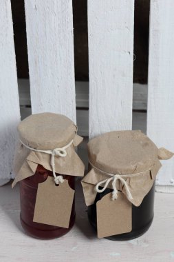 Reçel kavanozları, kağıt ile kaplıdır ve ikiyle bağlanmış. Dize asmak Craft etiketleri. Ahşap tahtaları arka planda.