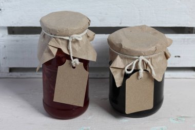 Reçel kavanozları, kağıt ile kaplıdır ve ikiyle bağlanmış. Dize asmak Craft etiketleri. Ahşap tahtaları arka planda.