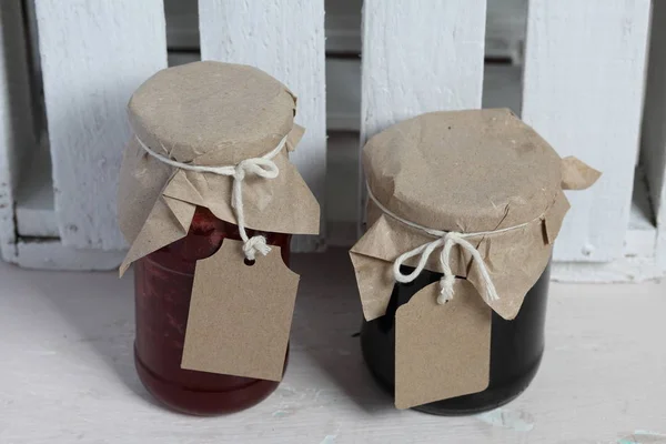 Reçel kavanozları, kağıt ile kaplıdır ve ikiyle bağlanmış. Dize asmak Craft etiketleri. Ahşap tahtaları arka planda.