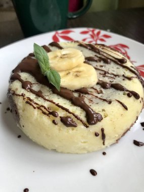 Muz Magcake. Çikolata, muz dilimleri ve nane ile dekore edilmiş.