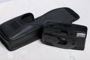 Eski film kamera analog 35mm. Masanın yüzeyinde yatıyor. Onun için kapağın yanında.