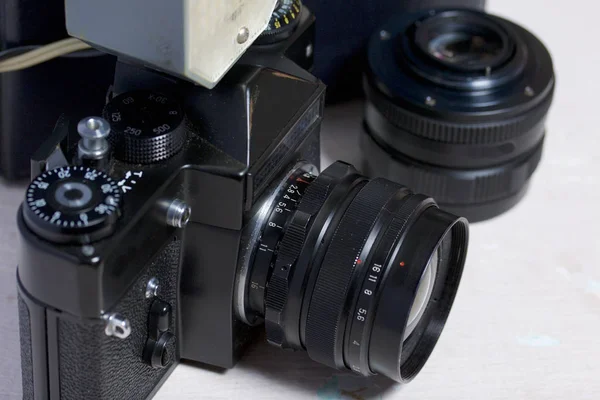 Câmera de filme antigo, lente removível e flash com fio. Deitam-se na superfície da mesa . — Fotografia de Stock