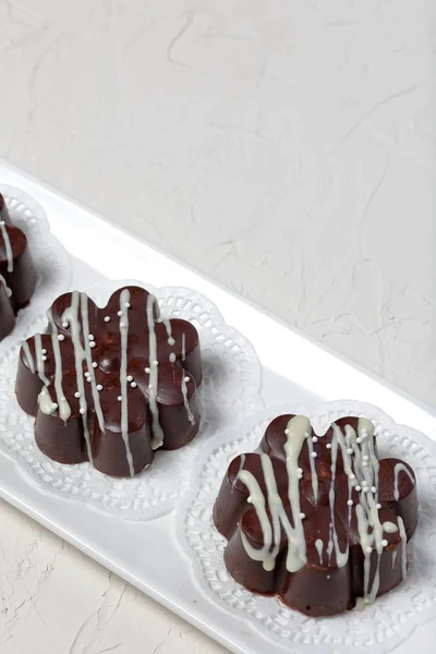 Čokoládový dezert ve tvaru květu. Tmavá čokoláda potažená. Zdobený bílou čokoládou a posypkami. — Stock fotografie
