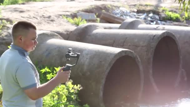 Young Man Takes Smartphone Mounted Bend Concrete Pipes Wastewater Visible — Stock Video