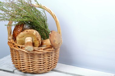 Porcini mantarı ve bir demet çiçek açan fundalıklı hasır sepet. Beyaz arka planda çekim yakın çekim.