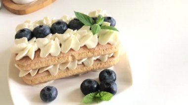 Kek savoiardi kurabiye ve krema yapılmış. Yaban mersini ve nane ile dekore edilmiştir. Tabaklarda yat..