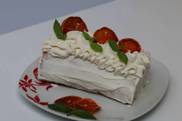 Gâteau à la crème éponge recouvert de crème et garni de tranches d'orange séchées et de feuilles de menthe fraîche . — Photo