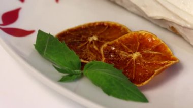 Sünger krema kek krema ile kaplanmış ve kurutulmuş portakal dilimleri ve taze nane yaprakları ile süslenmiş. Yakın çekim.