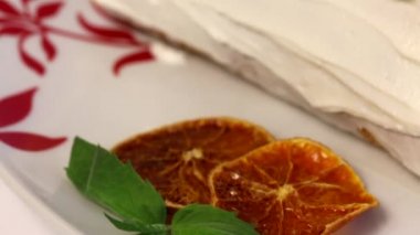 Sünger krema kek krema ile kaplanmış ve kurutulmuş portakal dilimleri ve taze nane yaprakları ile süslenmiş. Yakın çekim.