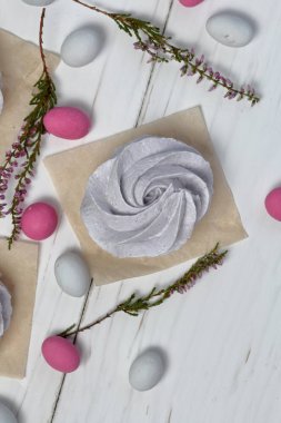 Beyaz boyalı tahtalarda taze yapılmış lavanta marshmallow. Yakındaki, farklı renklerde taşlar dekorasyon için dağınık. Heather dalları da görülebilir. Yukarıdan görüntüle.