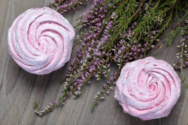 Pudra şekerinde pembe lokum. Dekorasyon yanında çiçek açan fundalık yatıyor.