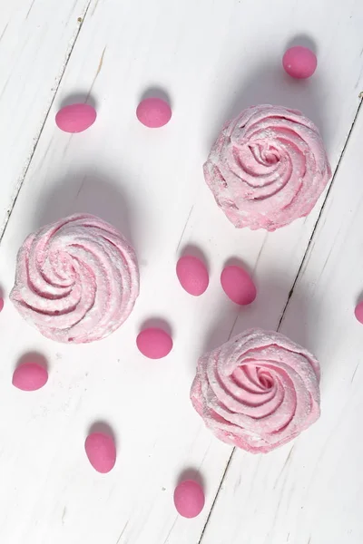 Malvaviscos rosados en azúcar glaseado. Mentiras sobre tablas pintadas de blanco. Piedras rosadas cercanas se dispersan para la decoración. Vista desde arriba . — Foto de Stock