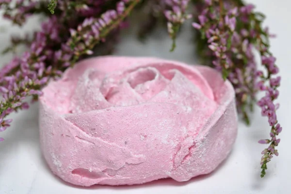 Los malvaviscos rosados en forma de la flor en el azúcar de guinda. Mentiras sobre tablas pintadas de blanco. Cerca se encuentra un ramo de brezo fresco . — Foto de Stock