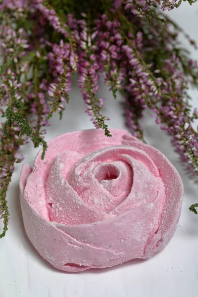 Los malvaviscos rosados en forma de la flor en el azúcar de guinda. Mentiras sobre tablas pintadas de blanco. Cerca se encuentra un ramo de brezo fresco . — Foto de Stock