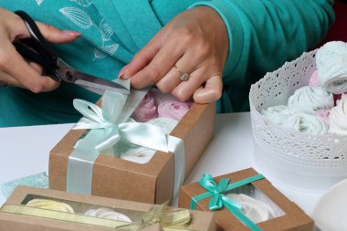 Kadın hediye kutularına farklı renklerde marshmallow koyar. Renkli kurdeleli bandaj kutuları. Bir yay kravat ve aşırı kesip.