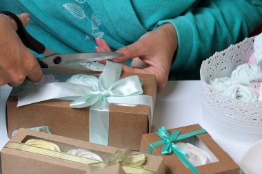 Kadın hediye kutularına farklı renklerde marshmallow koyar. Renkli kurdeleli bandaj kutuları. Bir yay kravat ve aşırı kesip.