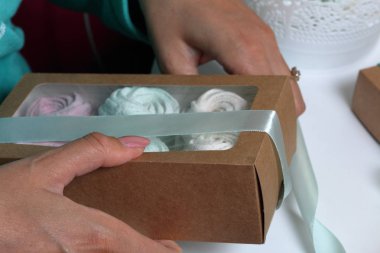 Kadın hediye kutularına farklı renklerde marshmallow koyar. Renkli kurdeleli bandaj kutuları.