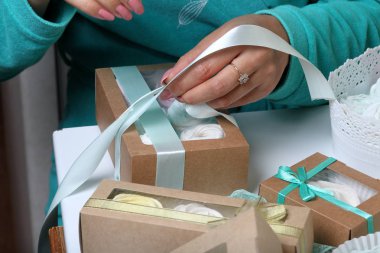 Kadın hediye kutularına farklı renklerde marshmallow koyar. Renkli kurdeleli bandaj kutuları.