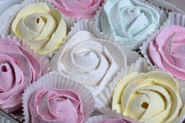 Marshmallows farklı renk ve şekillerde. Bazıları çiçek şeklinde. Hediye kutularına yığılmış. Yukarıdan görüntüle.