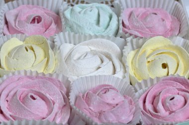 Marshmallows farklı renk ve şekillerde. Bazıları çiçek şeklinde. Hediye kutularına yığılmış. Yukarıdan görüntüle.