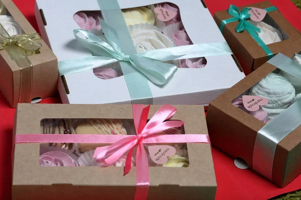 Malvaviscos de diferentes colores en cajas de regalo. Cajas atadas con una cinta de color atada a un lazo . — Foto de Stock