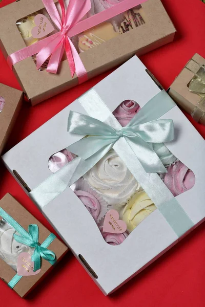 Marshmallows in verschiedenen Farben in Geschenkboxen. Schachteln, die mit einem farbigen Band an einer Schleife gebunden sind. Blick von oben. — Stockfoto