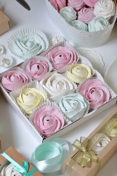 Marshmallow di diversi colori e forme. Alcuni a forma di fiore. Impilato in confezioni regalo. Nelle vicinanze ci sono nastri colorati per spogliatoi . — Foto Stock