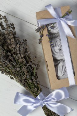 El sanatları ambalajında lavanta marshmallowları. Kurdele ile bağlanmış. Lavanta çeşitli dalları yay içine dokunmuş. Bir buket lavantanın yanında.