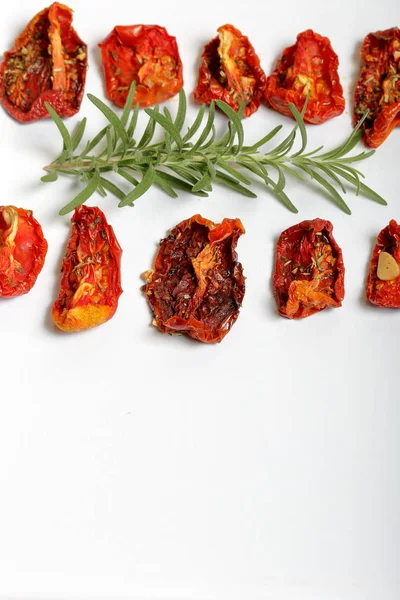 Hafif tepside baharat ve sarımsak ile güneşte kurutulmuş domates. Yakında taze biberiye yatıyor.