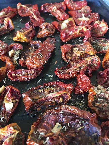 Sun-dried tomatoes with spices and garlic on a baking sheet. — Stock Photo, Image
