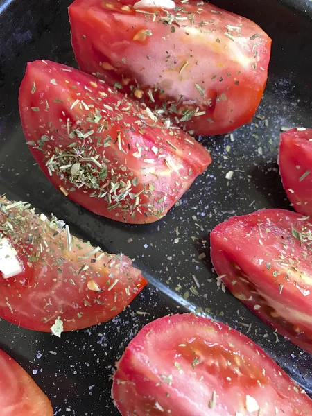 Plátky rajčat jsou rozloženy na pečicí plech. Posypané ochropeniny a česnekem. Příprava na sušení. — Stock fotografie