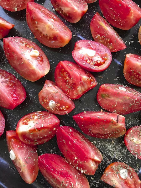 Slices of tomatoes are laid out on a baking sheet. Sprinkled with seasonings and garlic. Preparation for drying. — Stock Photo, Image