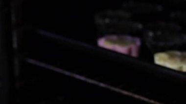 Bir kadın kek için pişmiş boşluklar ile fırın formları dışarı alır. Formlar fırın tepsisine.