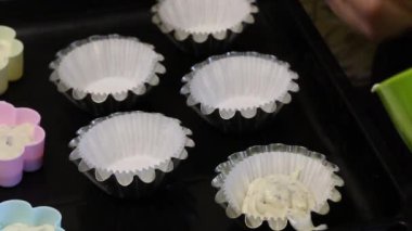 Bir kadın kek bir fırın tabağına hamur koyar. Farklı renklerde şekiller. Tatlı pişirmek.