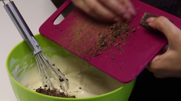 做甜点一个女人把黑巧克力片加到一个装有面团的容器里 搅拌一个搅拌 — 图库视频影像