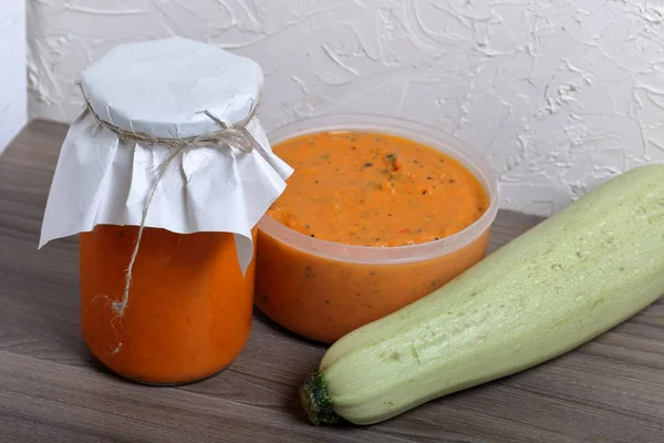 Preparações sazonais caseiras. No caviar de squash do banco. Nas proximidades encontra-se uma abobrinha fresca e caviar abobrinha em um recipiente aberto. O pescoço da lata é enrolado em papel e amarrado com uma corda . — Fotografia de Stock