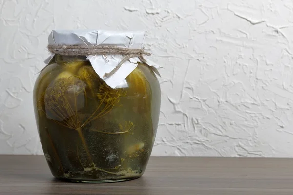 Preparaciones caseras de temporada. Pepinos en escabeche en un frasco de vidrio. El cuello de la lata está envuelto en papel y atado con una cuerda . — Foto de Stock