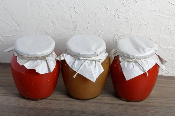 Preparações sazonais caseiras. Em bancos, legumes enlatados, frutas. O pescoço das latas é enrolado em papel e amarrado com corda . — Fotografia de Stock