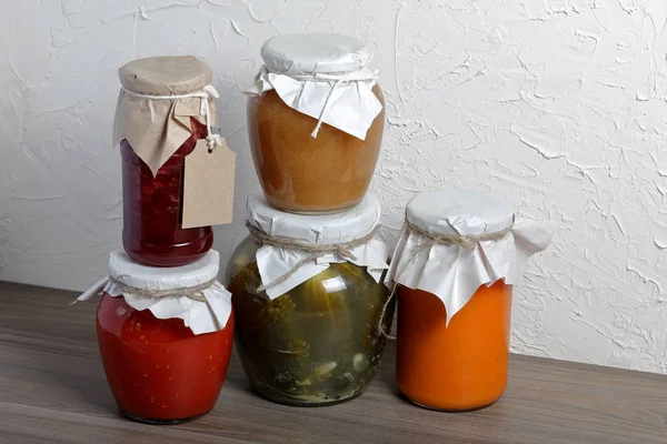 Preparações sazonais caseiras. Em bancos, legumes enlatados, frutas. O pescoço das latas é enrolado em papel e amarrado com corda . — Fotografia de Stock