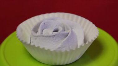 Kağıt sepetteki şekerlemeler. Dikey bir eksen etrafında döner. Mercan renginin arka planına karşı.