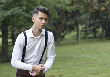 Şık giyimli genç adam bir parkta poz. korkuyla kameraya bakarak.