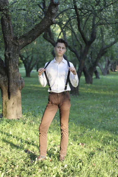 Jeune homme élégamment habillé posant dans un parc. Aide les mains à aider . — Photo