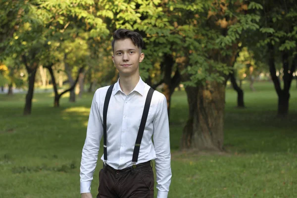 Jovem elegantemente vestido posando em um parque. Olha atentamente para o lado . — Fotografia de Stock