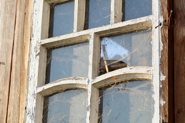 Altes Fenster mit Holzrahmen. Rahmen mit abblätternder Farbe. Staub und Spinnweben bedeckt. verschmutztes Glas. — Stockfoto