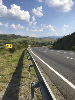 Transcarpathia'nın dağ manzaraları. Orman, çimenlerle kaplı tepeler arasında giden bir yol.
