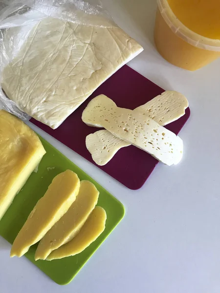 Queso feta casero y queso crema de leche de vaca. En una tabla de cortar hay trozos grandes de queso y varias rebanadas. Cerca del contenedor con miel . —  Fotos de Stock