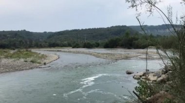 Bir dağ nehrinin su akıntısı. Vadide sakince akar. Ormanlarla birlikte büyümüş kayalık kıyılar görülebilir..
