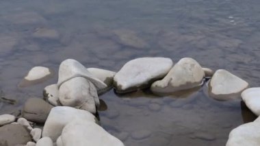 Bir dağ nehrinin su akıntısı. Vadide sakince akar. Kayalık kıyılar görülebilir. Ufukta dağlar ormanile büyümüş